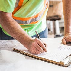 Image of a construction working making notes on a survey form.
